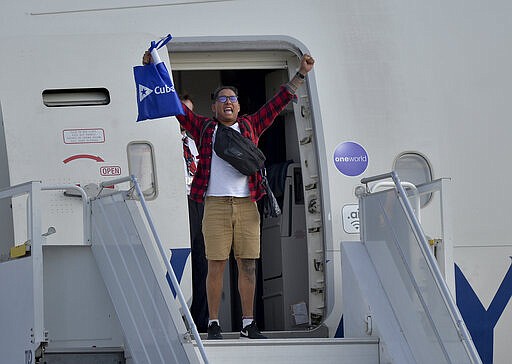 A passengers from the British cruise ship MS Braemar cheers from the plane's door before being flown to the UK, at the Jos&eacute; Mart&iacute; International Airport in Havana, Cuba, Wednesday, March 18, 2020. Cuba authorized on Wednesday the British cruise ship MS Braemar, with five confirmed cases of the new coronavirus and more than 1000 people on board, to dock on the island, from where its passengers will be repatriated by plane. (Yamil Lage/Pool photo via AP)