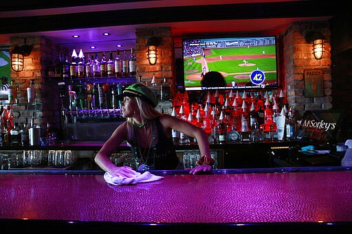 Kelli Rizza cleans the bar before closing the doors of McSorley's Beach Pub at 5 o'clock on Tuesday, March 17, 2020, in Fort Lauderdale Fla. Florida Gov. Ron DeSantis, released a statement saying that all bars and nightclubs throughout Florida will close for the next 30 days. (AP Photo/Brynn Anderson)