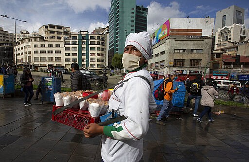 A fried chicken vendor wears a face mask as a preventative measure against the spread of the new coronavirus, in La Paz, Bolivia, Wedensday, March 18, 2020. Authorities have decreed a quarantine from 5pm to 5am in an attempt to stop the spread of the new coronavirus. The vast majority of people recover from the COVID-19 disease. (AP Photo/Juan Karita)