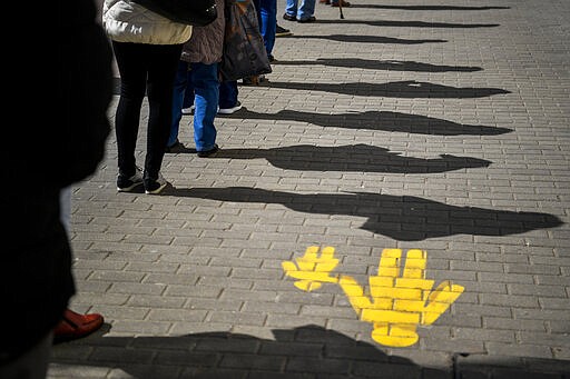 People keep their distance as they queue up in front of a post office in Debrecen, Hungary, March 16, 2020. (Zsolt Czegledi/MTI via AP)