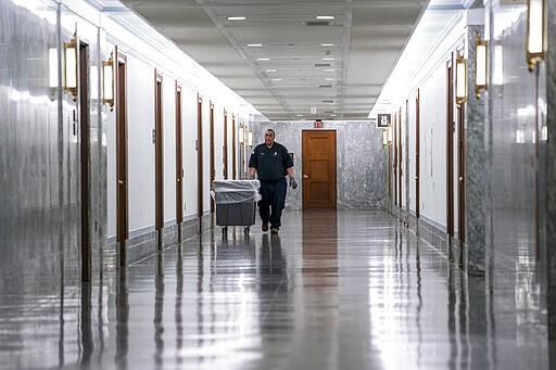 A workman walks through the empty corridors of the Dirksen Senate Office Building on Capitol Hill as lawmakers negotiate on the emergency coronavirus response legislation, in Washington, Wednesday, March 18, 2020. (AP Photo/J. Scott Applewhite)