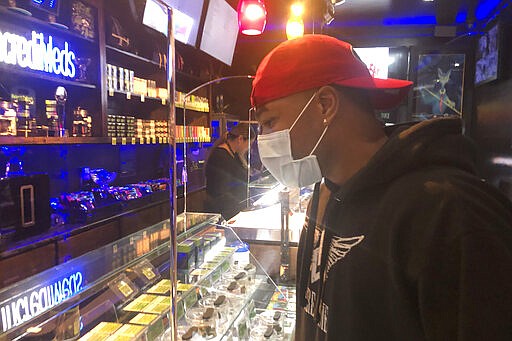 A customer who wished to remain unidentified wears a mask while shopping at The Green Cross cannabis dispensary in San Francisco, Wednesday, March 18, 2020. As about 7 million people in the San Francisco Bay Area are under shelter-in-place orders, only allowed to leave their homes for crucial needs in an attempt to slow virus spread, marijuana stores remain open and are being considered &quot;essential services.&quot; (AP Photo/Haven Daley)