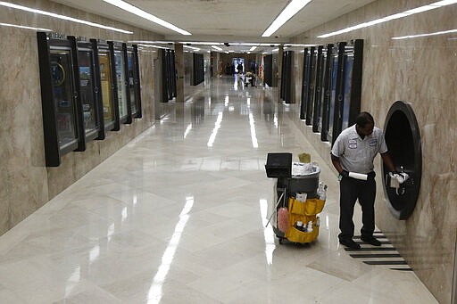 Custodian Anton Jennings cleans one of the water fountains on the first floor hallway of the state Capitol in Sacramento, Calif., Wednesday, March 18, 2020. In a precautionary effort to deal with the coronavirus, the Capitol and Legislative Office Building were closed to the public with only essential state workers and legislative employees allowed in until further notice, based on a &quot;stay at home&quot; directive issued by Sacramento County. (AP Photo/Rich Pedroncelli)
