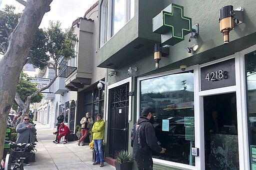 Customers maintain social distance while waiting to enter The Green Cross cannabis dispensary in San Francisco, Wednesday, March 18, 2020. As about 7 million people in the San Francisco Bay Area are under shelter-in-place orders, only allowed to leave their homes for crucial needs in an attempt to slow virus spread, marijuana stores remain open and are being considered &quot;essential services.&quot; (AP Photo/Haven Daley)