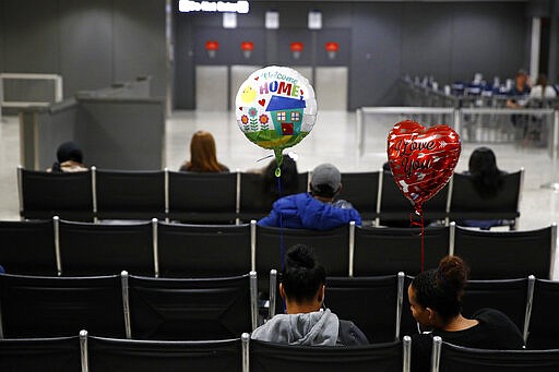 FILE - In this March 17, 2020, file photo, women wait with balloons in an arrival lounge at Dulles International Airport in Dulles, Va. (AP Photo/Patrick Semansky, File)