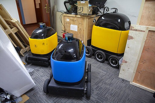 In this March 18, 2020, photo, robots are parked in a room at the offices of ZhenRobotics in Beijing. While other industries struggle, one robot maker says China's virus outbreak is boosting demand for his knee-high, bright yellow robots to deliver groceries and patrol malls for shoppers who fail to wear masks. (AP Photo/Mark Schiefelbein)