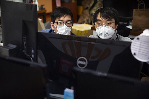 In this March 18, 2020, photo, people wearing face masks work at the offices of ZhenRobotics in Beijing. While other industries struggle, one robot maker says China's virus outbreak is boosting demand for his knee-high, bright yellow robots to deliver groceries and patrol malls for shoppers who fail to wear masks. (AP Photo/Mark Schiefelbein)