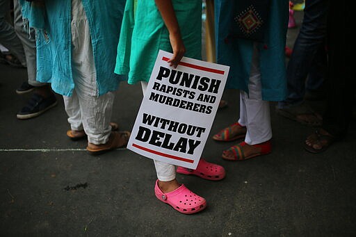 FILE - In this April 15, 2018, file photo, an Indian protester stands with a placard during a protest against two recently reported rape cases as they gather near the Indian parliament in New Delhi, India. Four men sentenced for capital punishment for the 2012 gang-rape of a 23-year-old physiotherapy student on a moving bus in New Delhi have been executed. The men were hanged Friday morning, March 20, 2020, at Tihar Jail in New Delhi. (AP Photo/Oinam Anand, File)