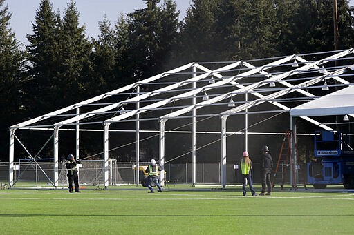 Workers erect a temporary field hospital for use by people unable to isolate and recover from COVID-19 in their own homes on a soccer field Thursday, March 19, 2020, in the Seattle suburb of Shoreline, Wash. The field hospital will provide up to 200 beds, according to a city website, and will house &quot;people exposed to, at risk of exposure, or becoming ill with the novel coronavirus.&quot; (AP Photo/Elaine Thompson)