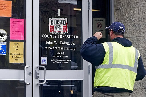 A man is confronted with a closed sign at the Douglas County Treasurer's office in Omaha, Neb., Wednesday, March 18, 2020. In-person services were suspended due to the coronavirus outbreak. (AP Photo/Nati Harnik)