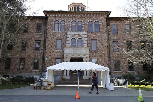 An employee walks near an entrance to Western State Hospital, Thursday, March 19, 2020, in Lakewood, Wash. A patient and a worker at the facility have tested positive for the new coronavirus. The tent shown behind him will eventually be used for screening employees for symptoms of the virus as they arrive for work. (AP Photo/Ted S. Warren)