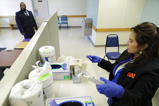 Relwende Guiguemde, left, waits to have his temperature taken by Angie Webb, right, a nurse at Western State Hospital, Thursday, March 19, 2020, as he arrives at a visitors' entrance for a job interview in Lakewood, Wash. A patient and a worker at the facility, the state's largest psychiatric hospital, have tested positive for the new coronavirus. (AP Photo/Ted S. Warren)