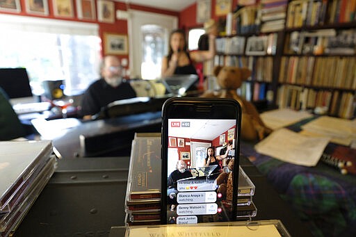 A smartphone broadcasts on Facebook Live pianist, composer and arranger Mike Greensill joining vocalist Kellie Fuller for a &quot;virtual cocktail party piano bar&quot; Thursday, March 19, 2020, in St. Helena, Calif. All public music venues in the Napa Valley have been closed due to the coronavirus restrictions and the pair held the virtual show as a way to keep performing. (AP Photo/Eric Risberg)