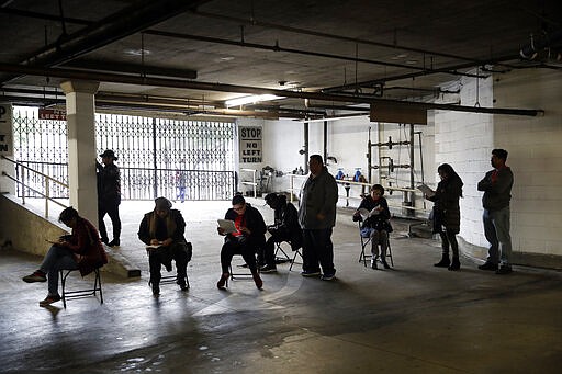 Unionized hospitality workers wait in line in a basement garage to apply for unemployment benefits at the Hospitality Training Academy Friday, March 13, 2020, in Los Angeles. Fearing a widespread health crisis, Californians moved broadly Friday to get in front of the spread of the coronavirus, shuttering schools that educate hundreds of thousands of students, urging the faithful to watch religious services online and postponing or scratching just about any event that could attract a big crowd. (AP Photo/Marcio Jose Sanchez)