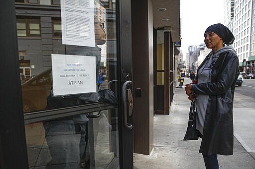 Visitors to the Department of Labor are turned away at the door by personnel due to closures over coronavirus concerns, Wednesday, March 18, 2020, in New York. Applications for jobless benefits are surging in some states as coronavirus concerns shake the U.S. economy. The sharp increase comes as governments have ordered millions of workers, students and shoppers to stay home as a precaution against spreading the virus that causes the COVID-19 disease. (AP Photo/John Minchillo)