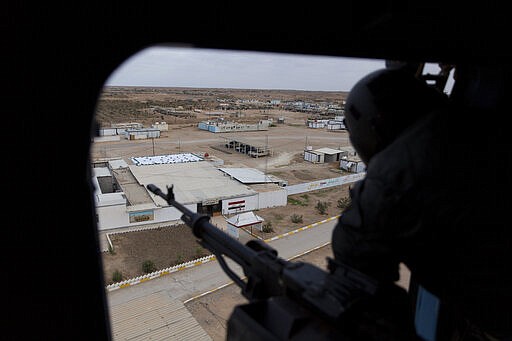 FILE - In this Dec. 29, 2019, file photo, an Iraqi soldier mans a machine gun onboard an army helicopter that is passing over the border town of al-Qaim during military operations of the Iraqi Army's Seventh Brigade, code named &quot;Will of Victory,&quot; in Anbar, Iraq. Troops from the U.S.-led coalition pulled out from a base in western Iraq on Thursday, March 19, 2020, as part of a planned drawdown, Iraqi and coalition officials said, while training activities by the coalition were suspended amid concerns about the coronavirus. (AP Photo/Nasser Nasser, File)