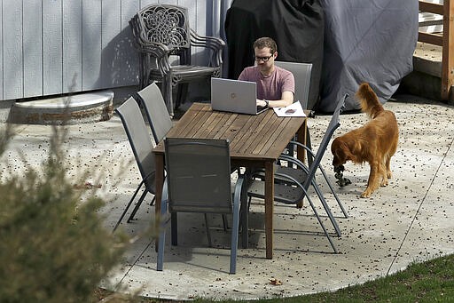 Erik Wray works on his computer in the backyard of his home Thursday, March 19, 2020, in Overland Park, Kan. Wray, a program manager for the Alzheimer's Association - Heart of America chapter, is among millions of workers toiling from home in an attempt to stem the spread of the coronavirus. (AP Photo/Charlie Riedel)