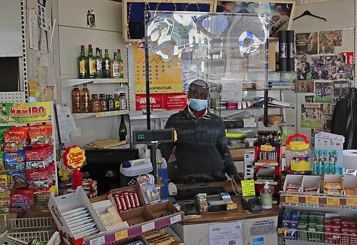 A Cashier wearing a face mask at a gas station stands behind a protective glass wall in Rueil-Malmaison, west of Paris, Thursday, March 19, 2020. France is imposing nationwide restrictions on how far from their homes people can go and for what purpose as part of the country's strategy to stop the spread of the new coronavirus. For most people, the new coronavirus causes only mild or moderate symptoms, such as fever and cough. For some, especially older adults and people with existing health problems, it can cause more severe illness, including pneumonia. (AP Photo/Michel Euler)