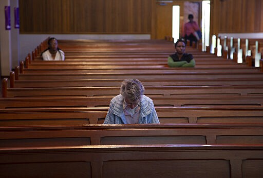 Few worshippers pray at the Rosebank Catholic Church In Johannesburg, South Africa, Thursday, March 19, 2020. South Africa imposed restrictions and banned gathering of 100 and more in a bid to prevent the spread of the coronavirus. For some people the COVID-19 coronavirus causes mild or moderate symptoms, but for some it causes severe illness. (AP Photo/Denis Farrell)