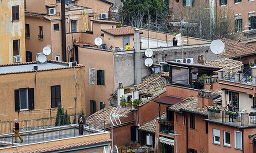 FILE - In this March 14, 2020, file photo, people clap their hands in appreciation for the efforts of Italian doctors and paramedics as they stand on their roof in Rome. At a time of unfathomable isolation, people in many European cities hit hard by the new coronavirus are taking at least a minute to come together in gratitude as they stand at open windows or on balconies singing, cheering and applauding. (AP Photo/Domenico Stinellis, File)