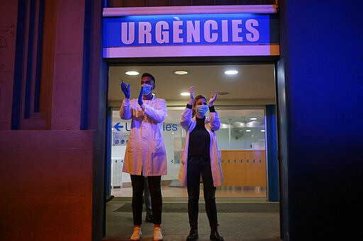 FILE - In this March 16, 2020, file photo, Health workers react as people applaud from their houses in support of the medical staff that are working in COVID-19 outbreak in Barcelona, Spain. At a time of unfathomable isolation, people in many European cities hit hard by the new coronavirus are taking at least a minute to come together in gratitude as they stand at open windows or on balconies singing, cheering and applauding. (AP Photo/Joan Mateu)