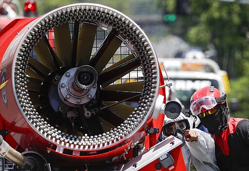 A man points beside a fireman as they prepare a machine that sprays disinfectants along a road to prevent the spread of the new coronavirus in Metro Manila, Philippines on Thursday, March 19, 2020. For most people, the new coronavirus causes only mild or moderate symptoms. For some, it can cause more severe illness, especially in older adults and people with existing health problems. (AP Photo/Aaron Favila)