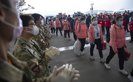 In this March 18, 2020 photo released by China's Xinhua News Agency, people applaud as departing medical workers enter Wuhan Tianhe International Airport in Wuhan in central China's Hubei Province. Last month, Wuhan was overwhelmed with thousands of new cases of coronavirus each day. But in a dramatic development that underscores just how much the outbreak has pivoted toward Europe and the United States, Chinese authorities said Thursday that the city and its surrounding province had no new cases to report. The virus causes only mild or moderate symptoms, such as fever and cough, for most people, but severe illness is more likely in the elderly and people with existing health problems. (Ke Hao/Xinhua via AP)