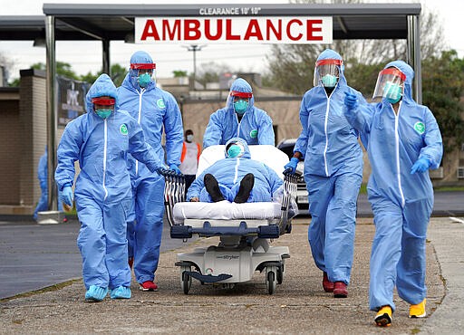 A person is taken on a stretcher into the United Memorial Medical Center after going through testing for COVID-19 Thursday, March 19, 2020, in Houston. People were lined up in their cars in a line that stretched over two miles to be tested in the drive-thru testing for coronavirus. (AP Photo/David J. Phillip)