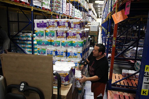 In this image made from video, Robert Buentello, an order selector, sorts through pallets of toilet paper at H-E-B&#146;s main distribution center in Houston on Wednesday, March 18, 2020. The Texas grocery chain says a surge of customer demand from panic buying due to concerns over the novel coronavirus has caused bottlenecks in the supply chain to its more than 400 stores throughout the state and Mexico. (AP Photo/John L. Mone)