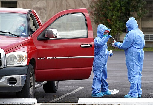 Healthcare professionals prepare to test a woman during drive thru testing for COVID-19 at United Memorial Medical Center Thursday, March 19, 2020, in Houston. The woman was later placed on a stretcher and taken into the facility for treatment. For most people, the coronavirus causes only mild or moderate symptoms, such as fever and cough. For some, especially older adults and people with existing health problems, it can cause more severe illness, including pneumonia. (AP Photo/David J. Phillip)