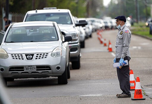 A man tries to talk to officials while standing in front of a line of cars stretching over two-miles to enter drive-thru testing for COVID-19 at United Memorial Medical Center, Thursday, March 19, 2020, in Houston. For most people, the coronavirus causes only mild or moderate symptoms, such as fever and cough. For some, especially older adults and people with existing health problems, it can cause more severe illness, including pneumonia. (AP Photo/David J. Phillip)