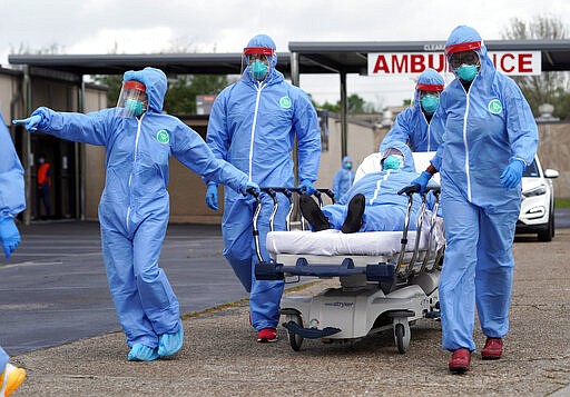 A woman is taken on a stretcher by healthcare professionals into the United Memorial Medical Center after going through testing for COVID-19 Thursday, March 19, 2020, in Houston. People were lined up in their cars in a line that stretched over two miles to be tested in the drive-thru testing for coronavirus. (AP Photo/David J. Phillip)