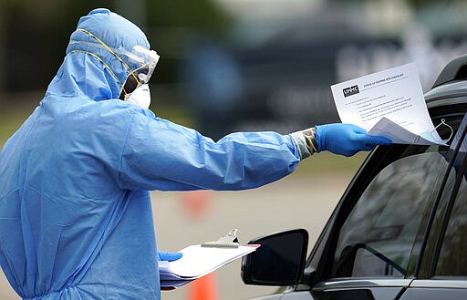 A healthcare professional hands a checklist to a patient at a drive-thru testing site for COVID-19 at United Memorial Medical Center Thursday, March 19, 2020, in Houston. For most people, the coronavirus causes only mild or moderate symptoms, such as fever and cough. For some, especially older adults and people with existing health problems, it can cause more severe illness, including pneumonia. (AP Photo/David J. Phillip)