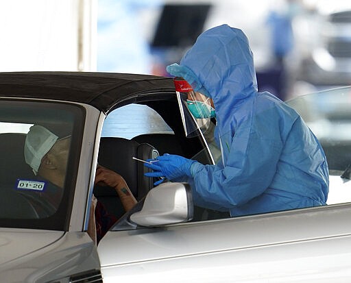 A patient is tested by a healthcare professional at a drive-thru testing site for COVID-19 at United Memorial Medical Center Thursday, March 19, 2020, in Houston. For most people, the coronavirus causes only mild or moderate symptoms, such as fever and cough. For some, especially older adults and people with existing health problems, it can cause more severe illness, including pneumonia. (AP Photo/David J. Phillip)