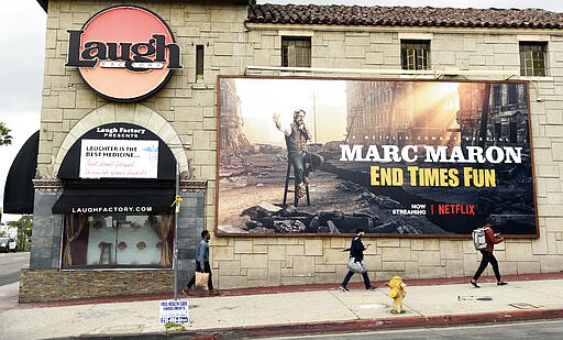 Pedestrians walk past the closed Laugh Factory comedy club, Monday, March 16, 2020, in Los Angeles. Los Angeles Mayor Eric Garcetti on Sunday ordered all of the city's bars, nightclubs, restaurants, gyms and entertainment venues to close in order to prevent the spread of the coronavirus. (AP Photo/Chris Pizzello)