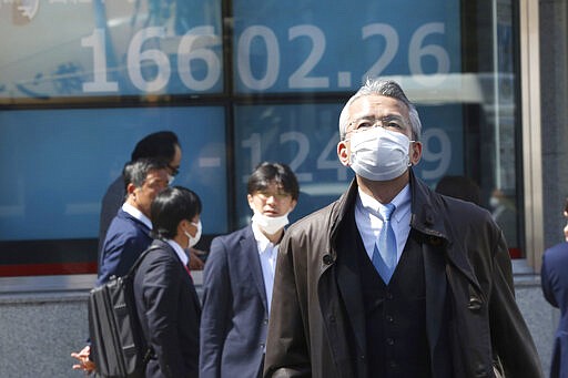 People walk by an electronic stock board of a securities firm in Tokyo, Thursday, March 19, 2020. Shares in Asia failed to hold onto opening gains on Thursday, skidding further after the latest selloff on Wall Street. (AP Photo/Koji Sasahara)