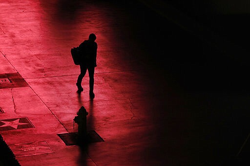 A person walks along the Las Vegas Strip devoid of the usual crowds after casinos have been ordered to shut down due to the coronavirus Wednesday, March 18, 2020, in Las Vegas. For most people, the new coronavirus causes only mild or moderate symptoms, such as fever and cough. For some, especially older adults and people with existing health problems, it can cause more severe illness, including pneumonia. (AP Photo/John Locher)