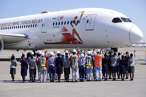 Ground crews of Japanese airlines wave to the special &quot;Tokyo 2020 Go&quot; aircraft that will transport the Olympic Flame to Japan after the Torch Handover Ceremony in Greece, on its departure at Haneda International Airport in Tokyo Wednesday, March 18, 2020. (AP Photo/Eugene Hoshiko)