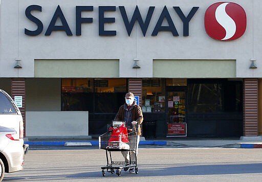 Wearing a mask for protection against the coronavirus, Henry Powell, heads to his car after shopping at a Safeway store in Sacramento, Calif., Thursday, March 19, 2020. Safeway is among the stores that are offering special shopping hours for seniors, like Powell, who is in his 70's, to get their groceries before opening to the rest of the public. (AP Photo/Rich Pedroncelli)