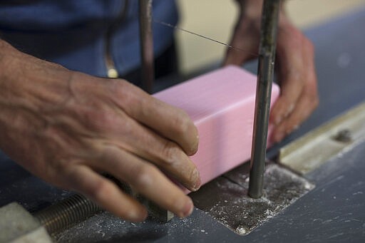 In this photo taken Monday March 16 2020, a factory worker cuts soap into bars at the Licorne soap factory in Marseille, southern France. Amid the rapid outbreak of the new coronavirus across Europe, the hallmark Marseille tradition of soap-making is enjoying a renaissance, as the French public rediscovers this essential local product. As French shops were ordered closed this week in a bid to counter the new coronavirus, Bruna's Savonnerie de la Licorne now runs its operations only for delivery, supplying pharmacies across France and handling individual orders placed through its online store. (AP Photo/Daniel Cole)