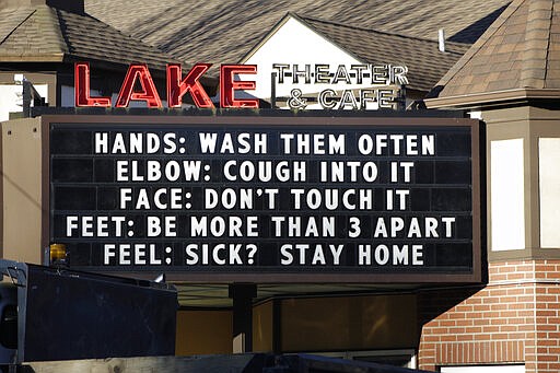 FILE - In this March 17, 2020 file photo, a marquee outside the Lake Theater &amp; Caf&eacute; in downtown Lake Oswego, Ore., reminds people to practice social distancing and stay home if sick. There's a new type of social policing out there that's developed almost as quickly as the viral disease that spurred its arrival. It's called &quot;quarantine shaming,&quot; calling out those who are leaving the house for daily activities or who aren't abiding by social distancing rules. And it's part of a new reality for Americans who must navigate a world of rapidly evolving social norms in the age of COVID-19. (AP Photo/Gillian Flaccus, File)