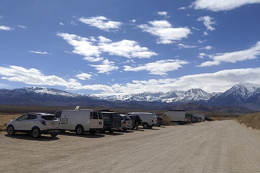 In this Wednesday, March 18, 2020 photo provided by Paula Flakser cars line along a dirt road near rock climbing spots outside Bishop, Calif. Local residents including Flakser were angry when hundreds of people from Los Angeles arrived in Bishop last weekend after schools announced closures due to the new coronavirus. Some local climbers took to online climbing sites and social media to shame the coronavirus vacationers and by Wednesday, the crowds had abated somewhat. (Paula Flakser via AP)