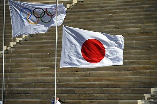 A Japan's flag is raised next to the Olympic flag during the Olympic flame handover ceremony for the 2020 Tokyo Summer Olympics, in Athens, Thursday March 19, 2020. (Aris Messinis/Pool via AP)