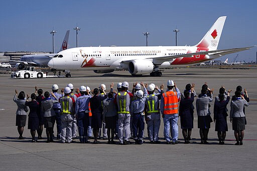 FIEL - In this March 18, 2020, file photo, ground crews of Japanese airlines wave to the special &quot;Tokyo 2020 Go&quot; aircraft that will transport the Olympic Flame to Japan after the Torch Handover Ceremony in Greece, departs at Haneda International Airport in Tokyo. The Olympic flame from Greece is set to arrive in Japan even as the opening of the the Tokyo Games in four months is in doubt with more voices suggesting the games should to be postponed or canceled because of the worldwide virus pandemic. (AP Photo/Eugene Hoshiko, File)