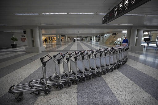 A worker pushes trollies at an empty terminal hall of the Rafik Hariri International Airport, in Beirut, Lebanon, Thursday, March 19, 2020. The Lebanese government decided to shut down the airport, ports and borders and ordered its citizens to stay home as the small country of nearly 5 million grappled with containing the coronavirus. (AP Photo/Hassan Ammar)