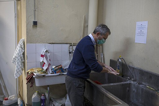 In this photo taken Monday March 16 2020, fourth generation soap maker Serge Bruna washes his hands in his family owned Licorne soap factory in Marseille, southern France. Amid the rapid outbreak of the new coronavirus across Europe, the hallmark Marseille tradition of soap-making is enjoying a renaissance, as the French public rediscovers this essential local product. As French shops were ordered closed this week in a bid to counter the new coronavirus, Bruna's Savonnerie de la Licorne now runs its operations only for delivery, supplying pharmacies across France and handling individual orders placed through its online store. (AP Photo/Daniel Cole)
