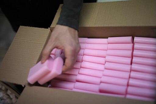 In this photo taken Monday March 16 2020 freshly cut soap bars are packed away at the Licorne soap factory in Marseille, southern France. Amid the rapid outbreak of the new coronavirus across Europe, the hallmark Marseille tradition of soap-making is enjoying a renaissance, as the French public rediscovers this essential local product. As French shops were ordered closed this week in a bid to counter the new coronavirus, Bruna's Savonnerie de la Licorne now runs its operations only for delivery, supplying pharmacies across France and handling individual orders placed through its online store. (AP Photo/Daniel Cole)