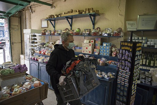 In this photo taken Tuesday March 17 2020, fourth generation soap maker, Serge Bruna empties the last delivery truck an hour before the nationwide confinement measures are set to go into effect in Marseille, southern France. Amid the rapid outbreak of the new coronavirus across Europe, the hallmark Marseille tradition of soap-making is enjoying a renaissance, as the French public rediscovers this essential local product. (AP Photo/Daniel Cole)