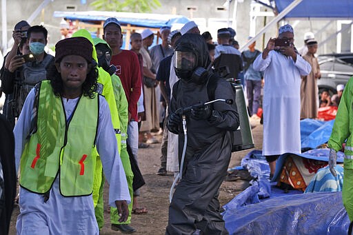 A paramilitary police officer in a hazmat suit walks among pilgrims as he disinfects a tent built on a field where a mass congregation is supposed to be held in Gowa, South Sulawesi, Indonesia, Thursday, March 19, 2020. Indonesia halted the congregation of thousands of Muslim pilgrims and began quarantining and checking their health Thursday to prevent the spread of the new coronavirus. The vast majority of people recover from the new coronavirus. According to the World Health Organization, most people recover in about two to six weeks, depending on the severity of the illness. (AP Photo/Syaief)