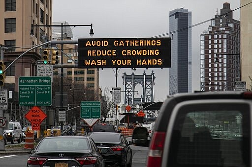 The Manhattan bridge is seen in the background of a flashing sign urging commuters to avoid gatherings, reduce crowding and to wash hands in the Brooklyn borough of New York, on Thursday, March 19, 2020. In a matter of days, millions of Americans have seen their lives upended by measures to curb the spread of the new coronavirus. For most people, the new coronavirus causes only mild or moderate symptoms. For some it can cause more severe illness. (AP Photo/Wong Maye-E)